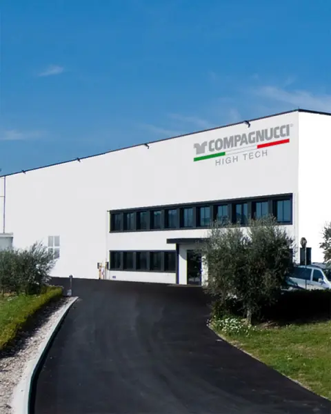 La sede di Compagnucci High Tech: l'edificio bianco con l'insegna dell'azienda, il viale d'accesso e gli ulivi all'ingresso