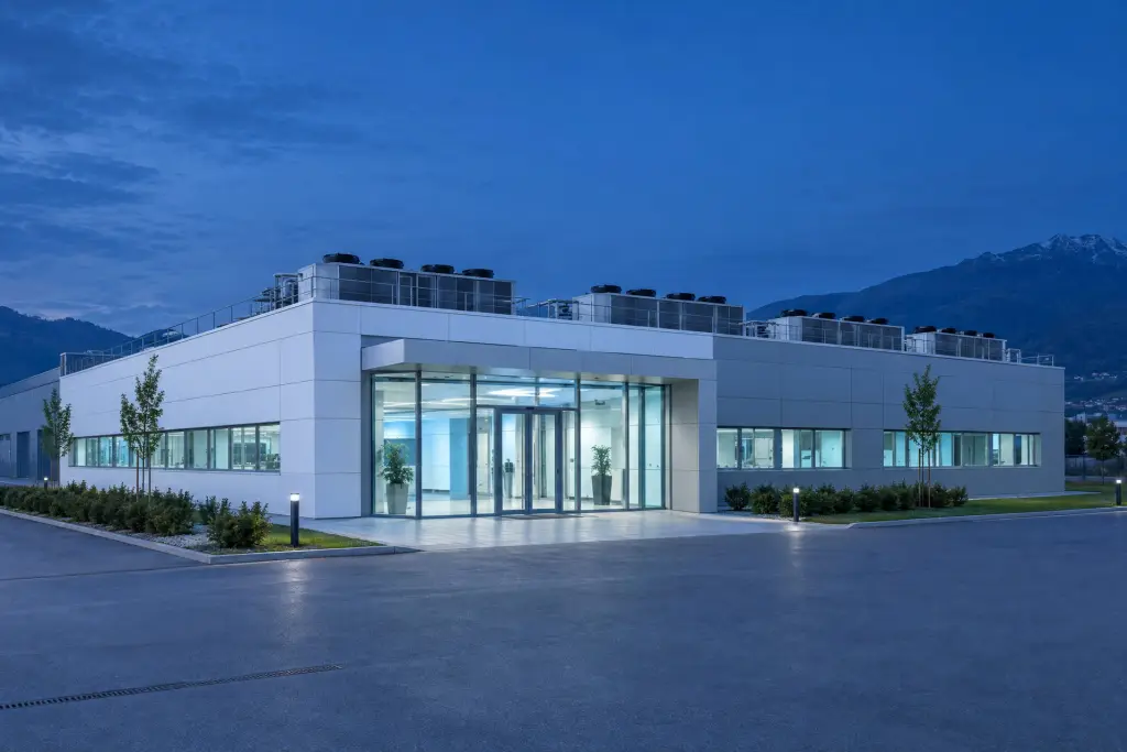 L'esterno di un edificio tecnico all'ora blu, con l'ingresso vetrato illuminato